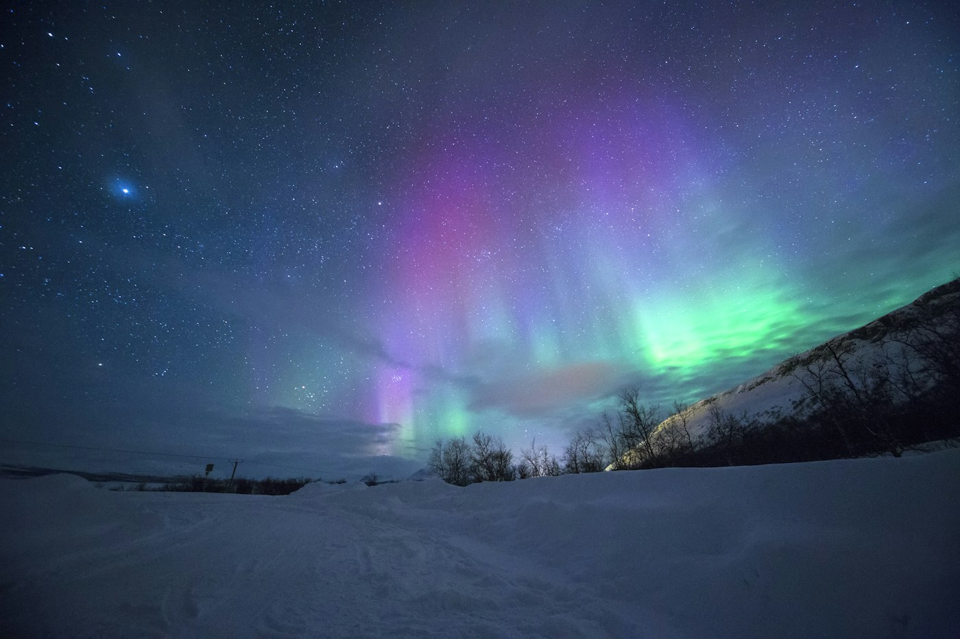 Northern lights above a snowy mountain landscape
